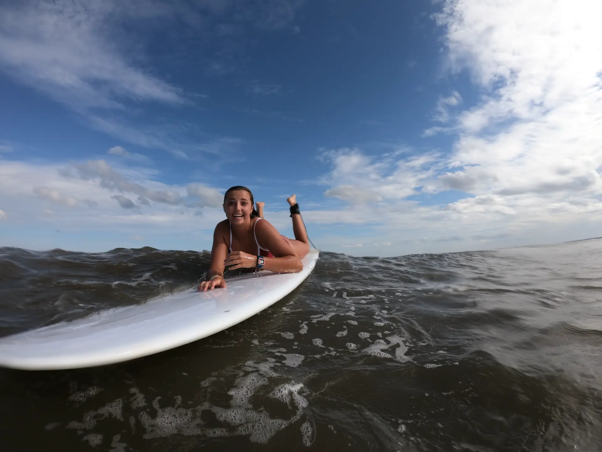 A Maritime Gal smiling on a surfboard in the Atlantic