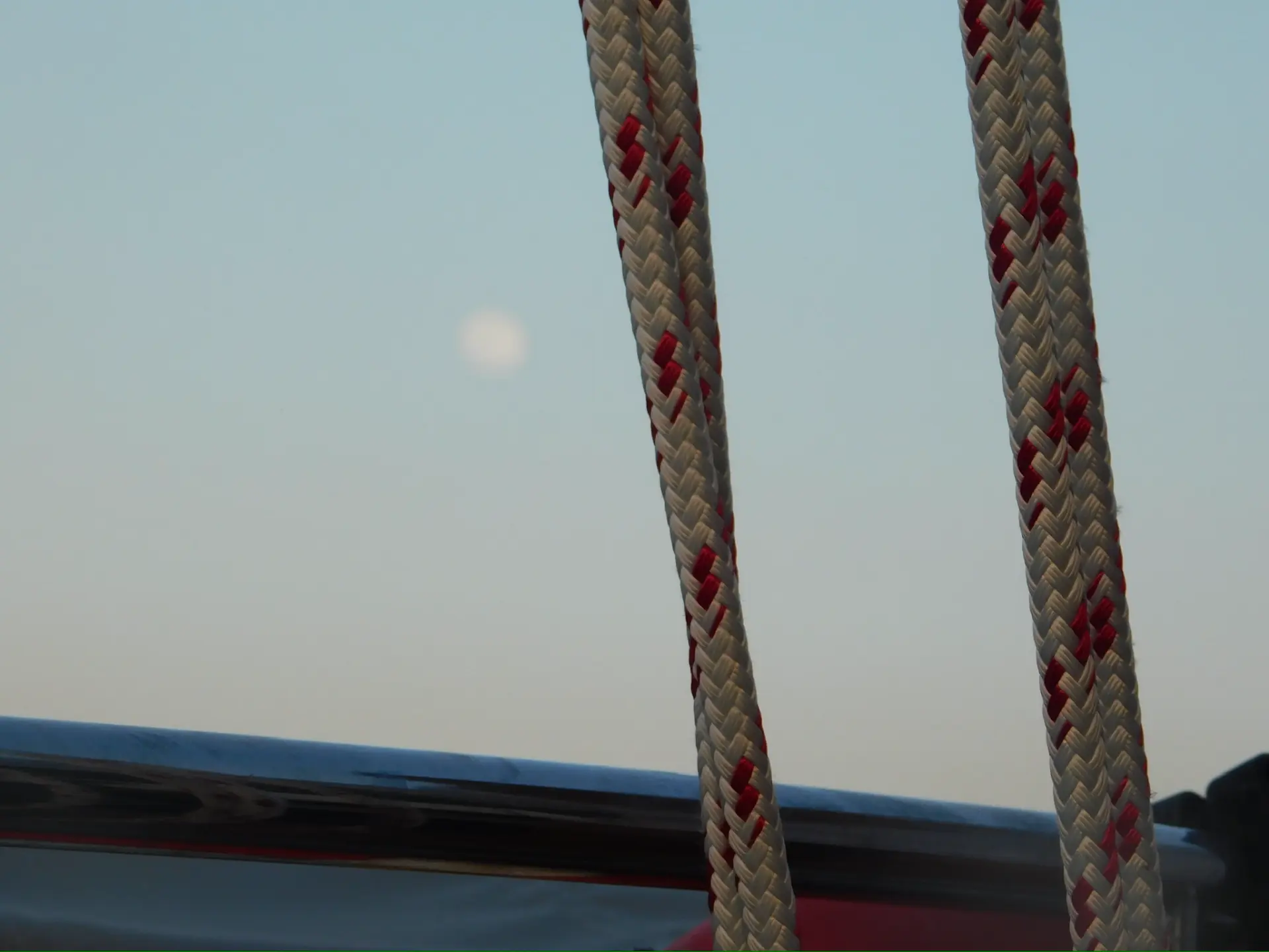 Braided dock lines against a soft harbor sky with the moon