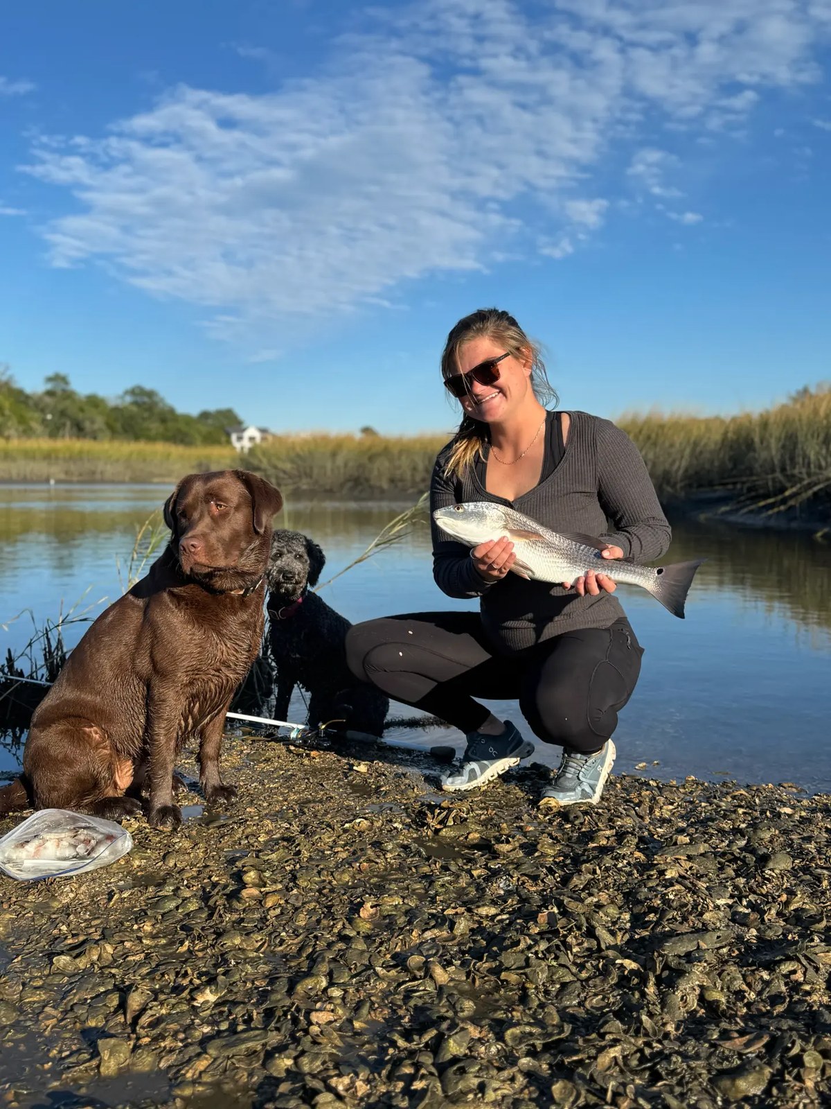 A Maritime Gal showing off a redfish on the marsh flats with her fishing pups
