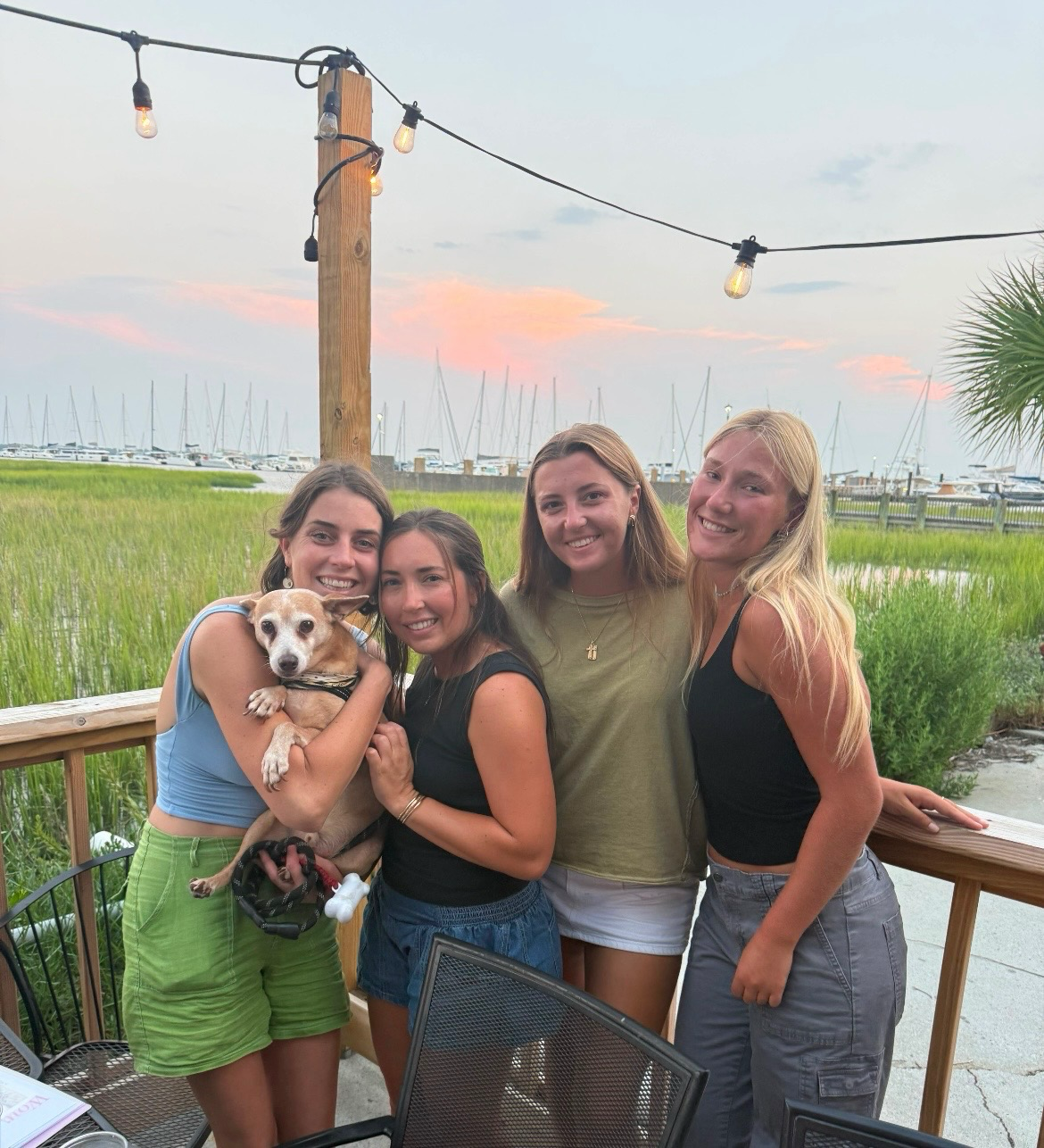 Four Maritime Gals and a pup dockside at sunset with Charleston harbor behind them
